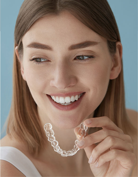 a girl smiling and holding invisalign at smith dentalworks