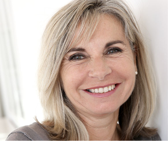 An older woman with a white, beautiful smile thanks to implant restorations after an extraction