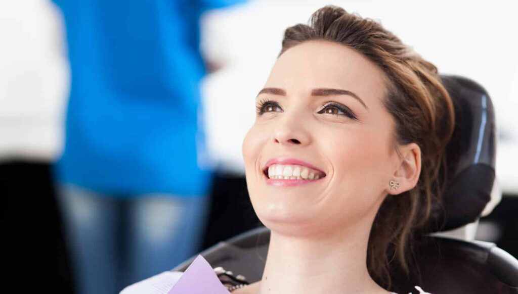 a woman in a black dental chair smiling at smith dentalworks