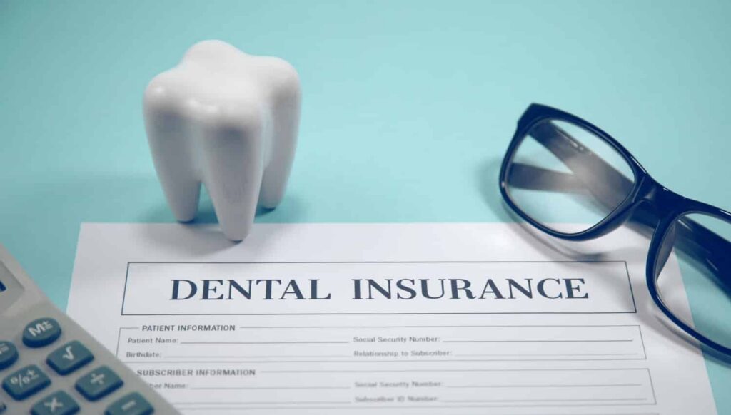 a dental insurance form with a model of a tooth and glasses next to it