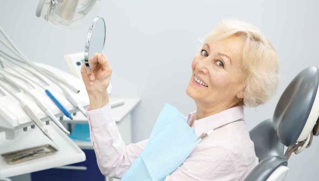 an elderly woman smiling after getting implant dentures at smith dentalworks