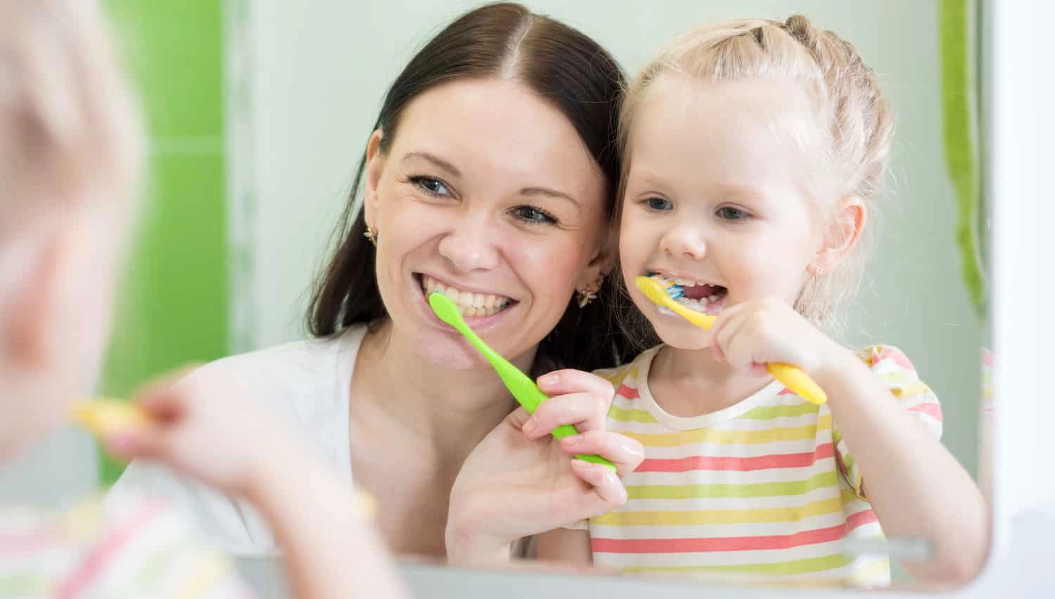 a mother practicing good dental hygiene with her young daughter
