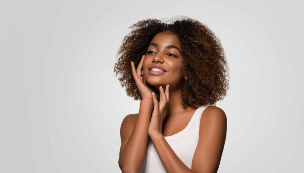 Smiling woman with curly hair showcasing confidence, representing benefits of smile makeovers in cosmetic dentistry.
