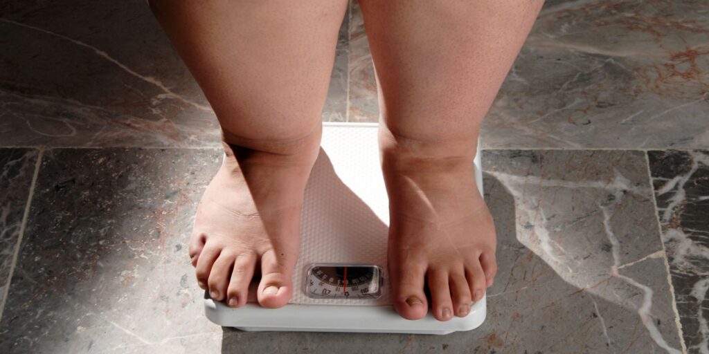 Feet on a scale highlighting the relationship between weight and sleep apnea risk factors.