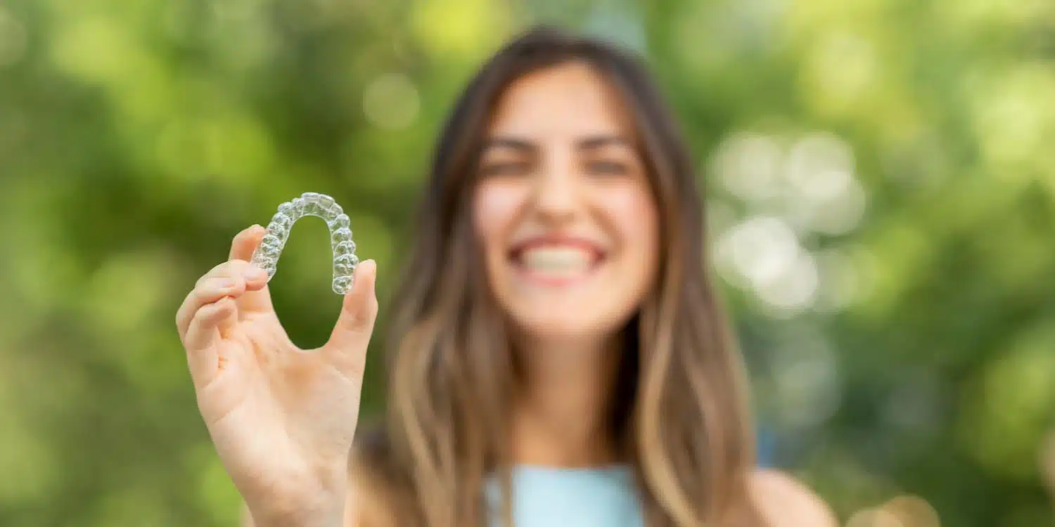 a woman holding up invisible orthodontics invisalign trays