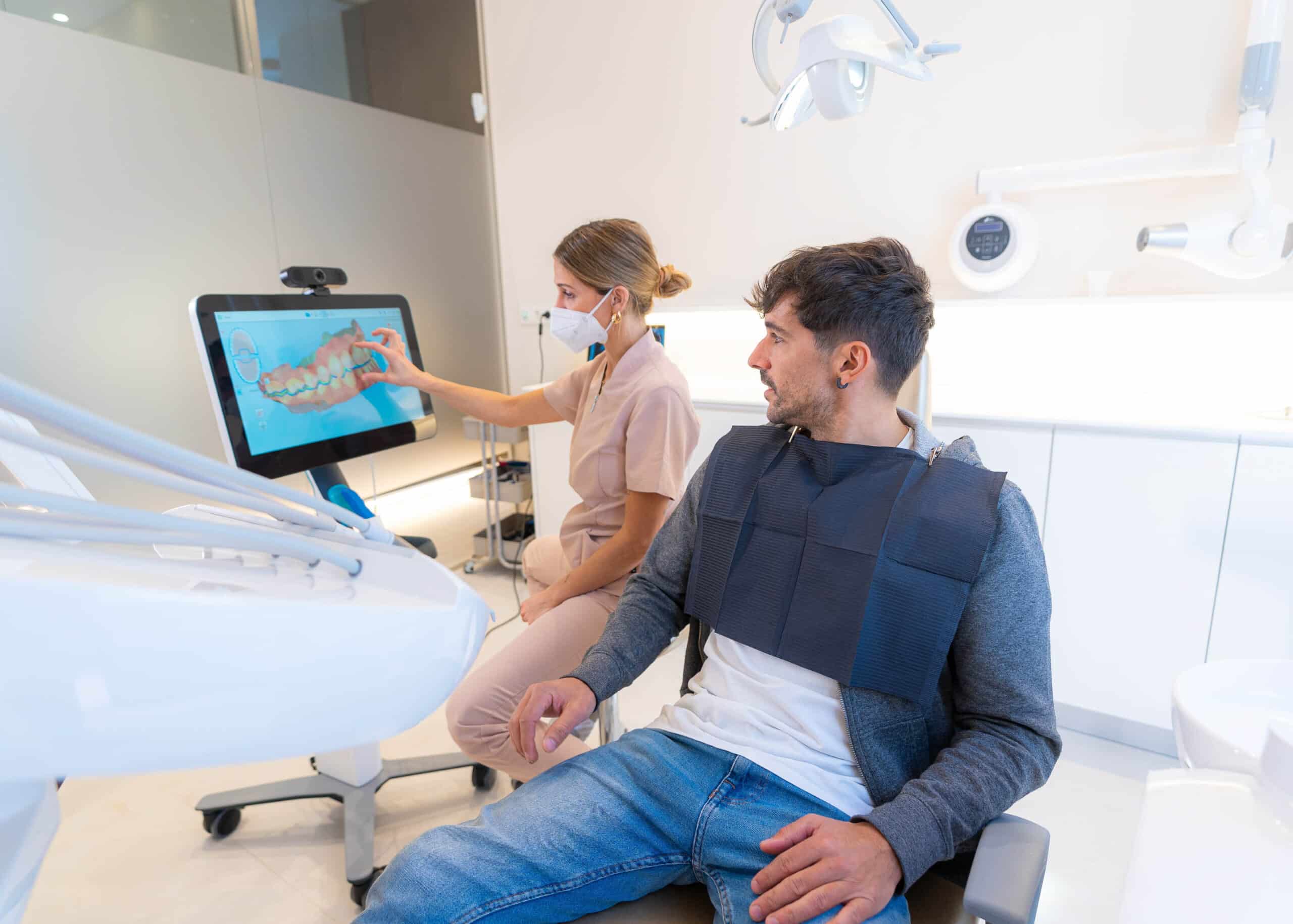 Dental professional explaining treatment options using digital technology to patient in modern dental office.