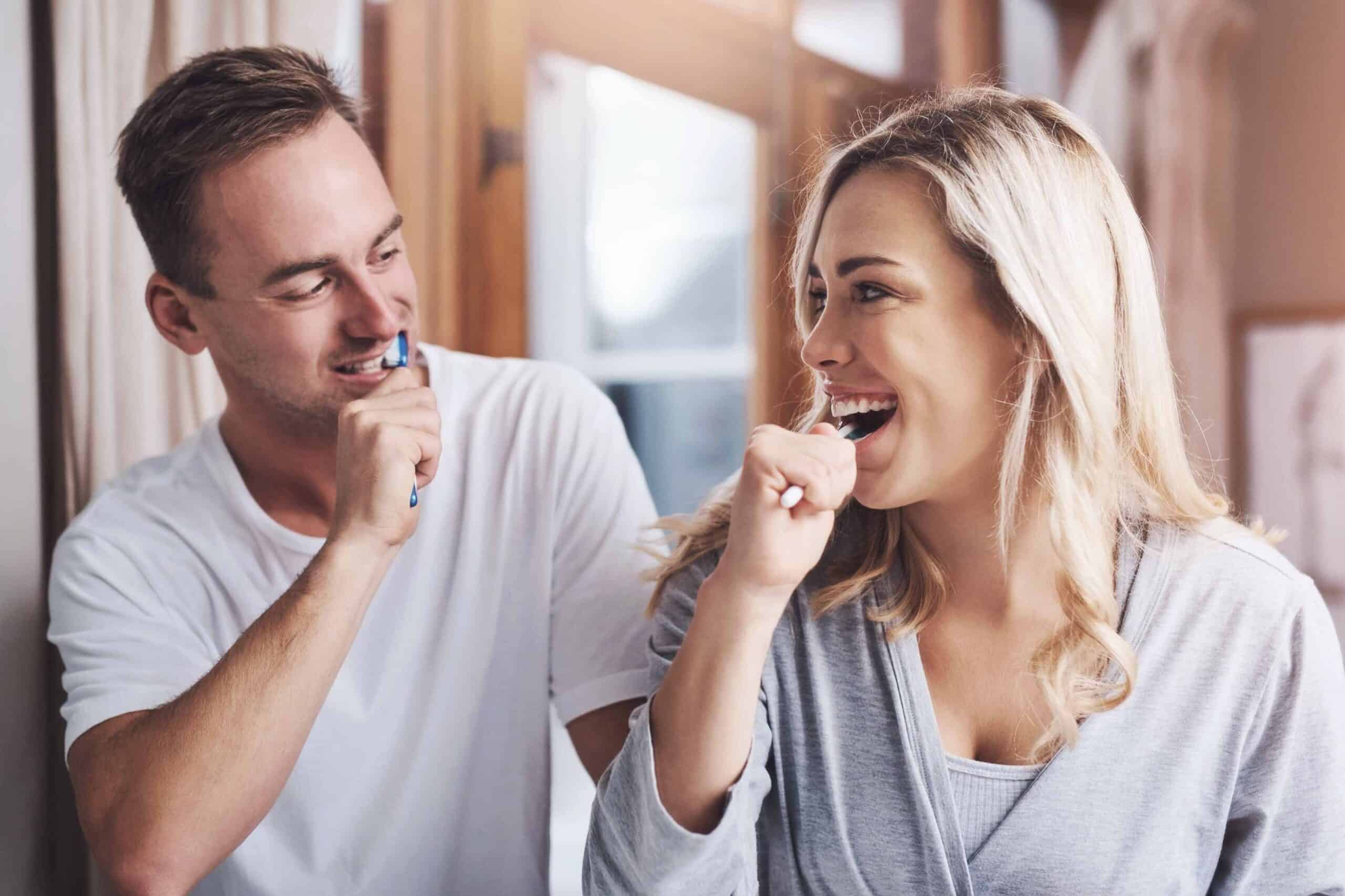 Couple brushing teeth together, promoting oral hygiene and healthy dental habits.