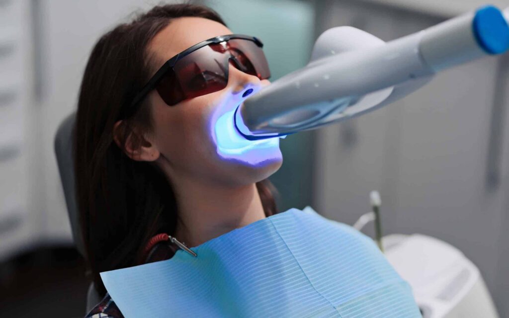 Woman undergoing laser dental treatment with Solea® Laser, wearing protective glasses, in a modern dental office setting.