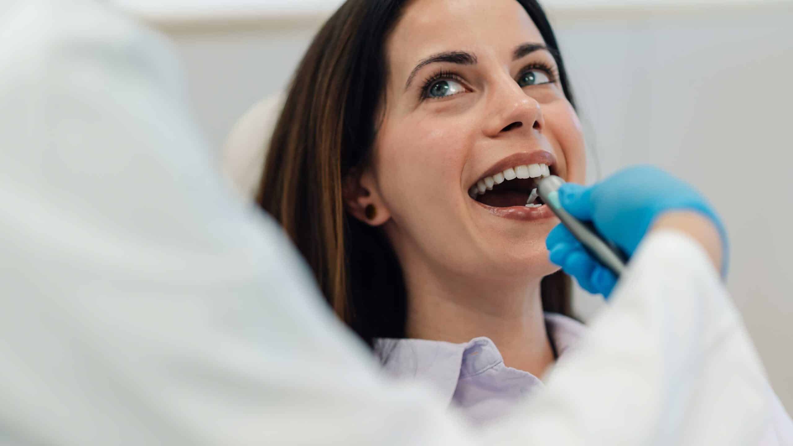 Woman at dental appointment receiving oral examination, emphasizing importance of regular dental visits for maintaining oral health and preventing future issues.