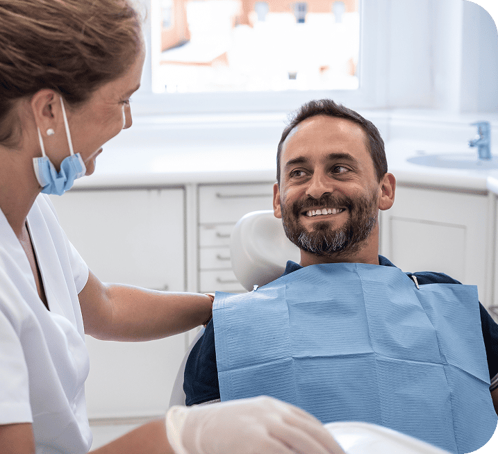 Patient smiling in dental chair with hygienist, preparing for tooth extraction at Smith Dentalworks in Oro Valley.
