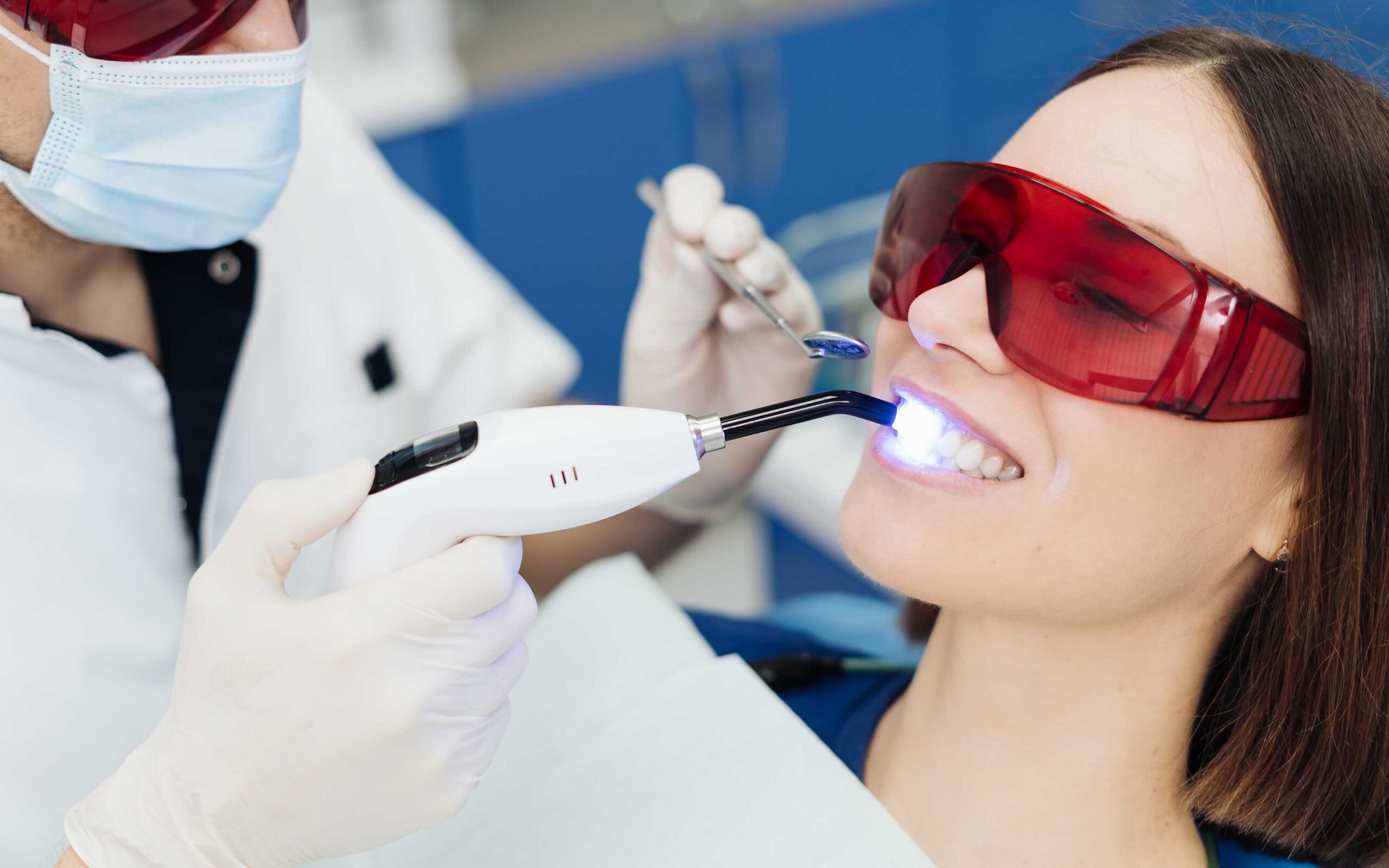 Laser dentistry procedure with patient wearing protective glasses, dental professional using a laser tool for treatment.